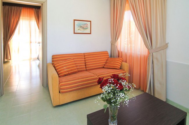 Soggiorno con divano a righe e vaso di fiori.