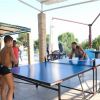 Ragazzi che giocano a ping pong su un tavolo blu all'aperto.