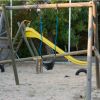 Un parco giochi con altalena e scivolo giallo.
