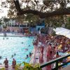 Piscina affollata con persone e lettini a bordo vasca.