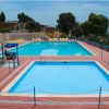Due piscine su un patio rosso con lettini gialli intorno.