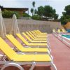 File di lettini gialli lungo una piscina con ombrelloni bianchi.