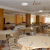 Sala da pranzo con tavoli rotondi apparecchiati.