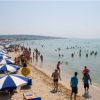 Spiaggia affollata con ombrelloni blu e bianchi.