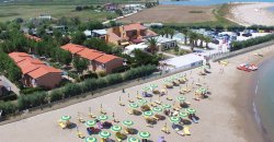 Complesso residenziale vicino a una spiaggia con ombrelloni.