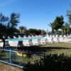 Piscina all'aperto con sdraio, recinzione e alberi attorno.