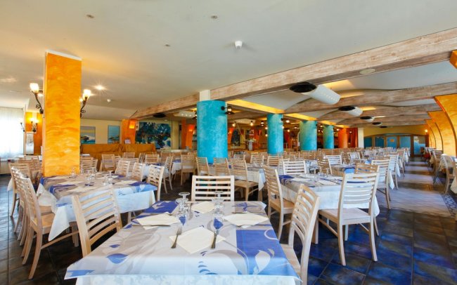 Ristorante ampio con tavoli apparecchiati e colonne colorate.