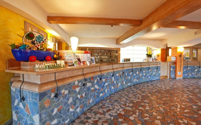 Reception con banco in pietra e decorazioni colorate.