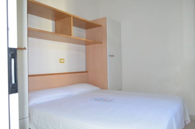 Camera da letto con letto matrimoniale e scaffale.