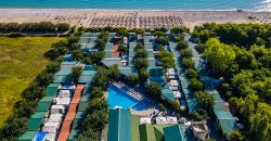 Vista aerea di un villaggio vacanze con piscina e spiaggia attrezzata.
