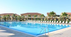 Ampia piscina all'aperto con lettini e ombrelloni intorno.