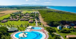 Veduta dall'alto di piscine circolari e paesaggio verde con mare all'orizzonte.