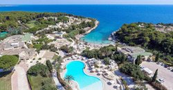Vista aerea di un resort costiero con una grande piscina e una baia turchese.