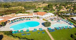 Complesso con grande piscina circolare e ombrelloni blu, circondato dal verde.